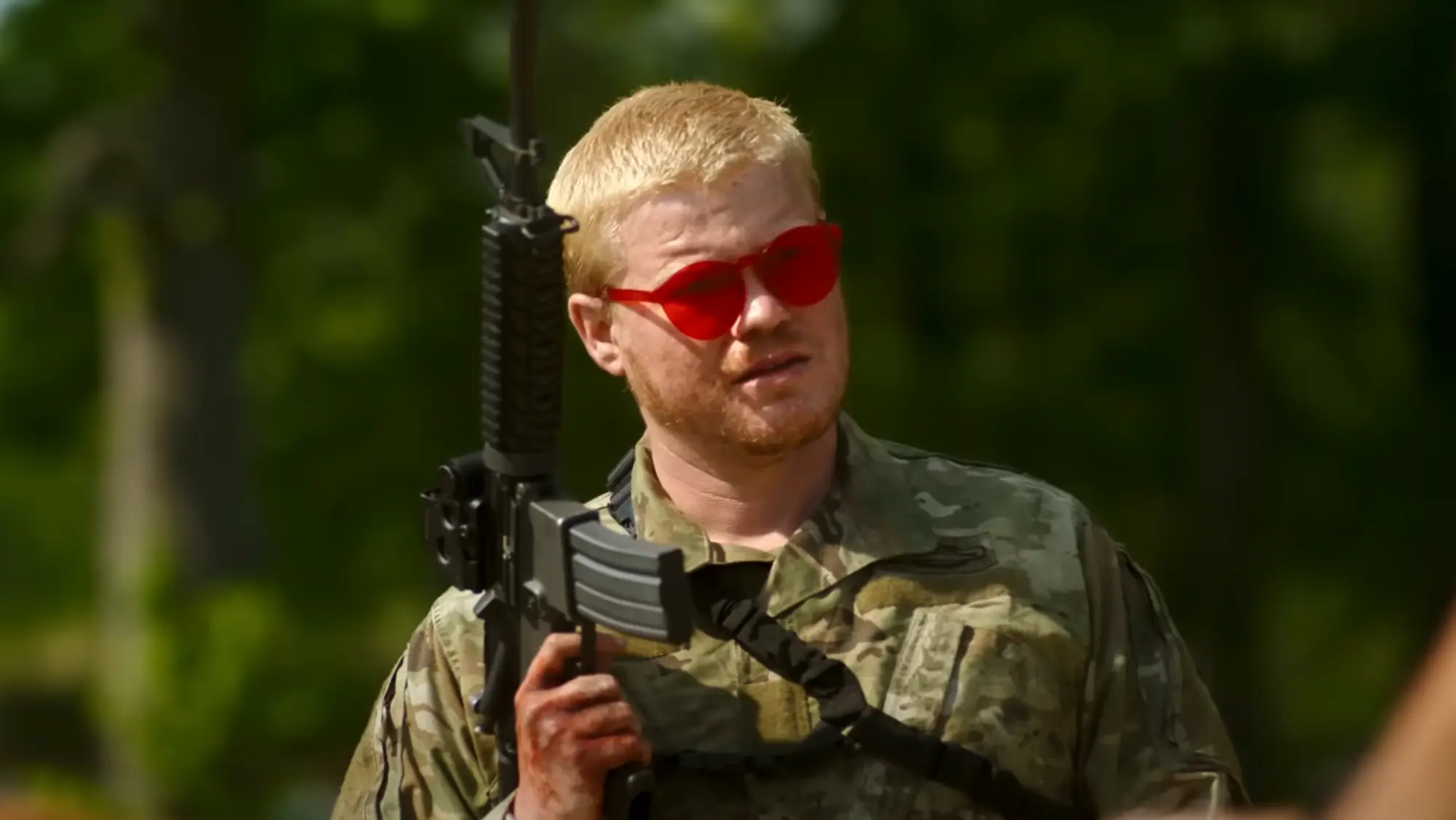 Jesse Plemons con un arma en Kristen Dunst protegiendose de una explosión en Civil War la película de Alex Garland